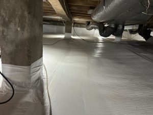 A clean, encapsulated crawl space with white plastic lining covers the floor and pillars. Exposed wooden beams and insulated ducts are visible overhead.