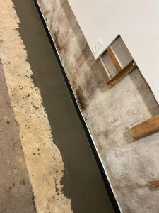 Fresh concrete covering a newly installed interior basement drainage system designed to prevent water intrusion and moisture buildup.