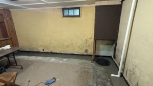 Basement showing moisture stains and waterproofing trench during repair for what causes a musty smell in your basement