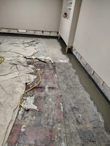 Interior drainage system installation in Upper St. Clair, PA with newly poured concrete covering the perimeter drainage channel to protect the finished basement from water intrusion.